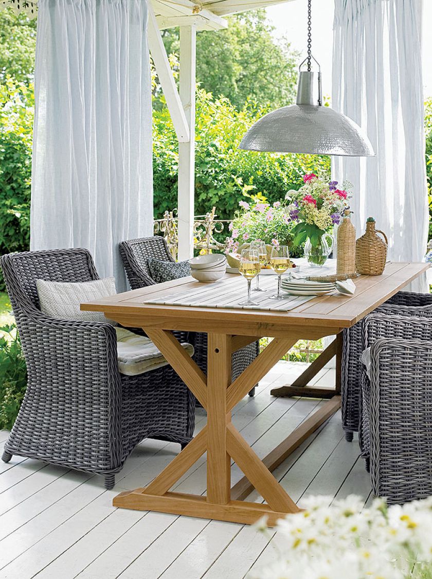 Rattanowe lub wiklinowe fotele i stabilny drewniany stół: trochę Prowansja, trochę Sakndynawia.