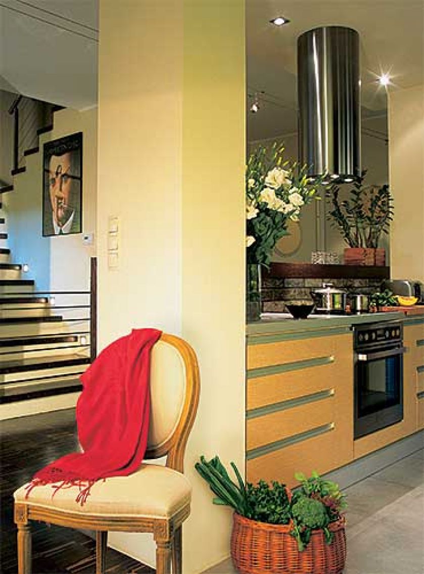 Geometryczne formy schodow i kuchennych szafek ocieplają kolorowe dodatki.