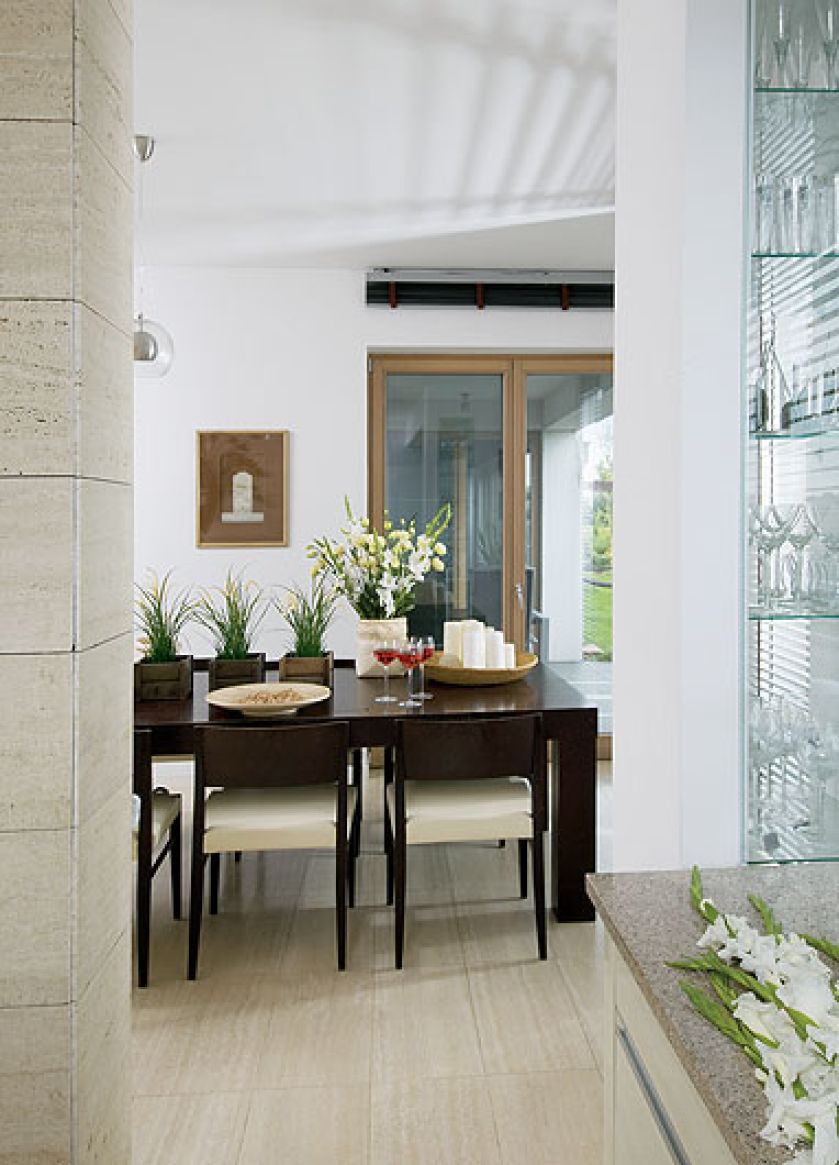 Do jasnych ścian i podłóg dobrano dla kontrastu ciemonobrązowy stół od Vinotti.