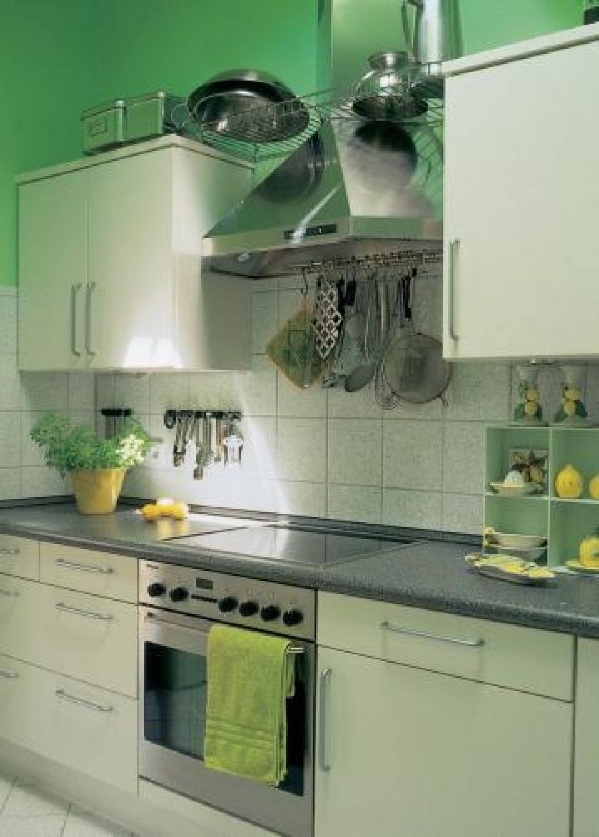 W kuchni wrażenie świeżości i przestrzeni dają proste białe szafki i chłodna zieleń ścian.