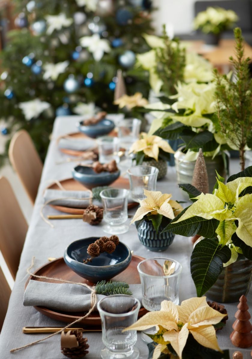 Drewno, ceramika, błyszczące złote sztućce, szyszki i gałązki tworzą aranżację na tym świątecznym stole, która
