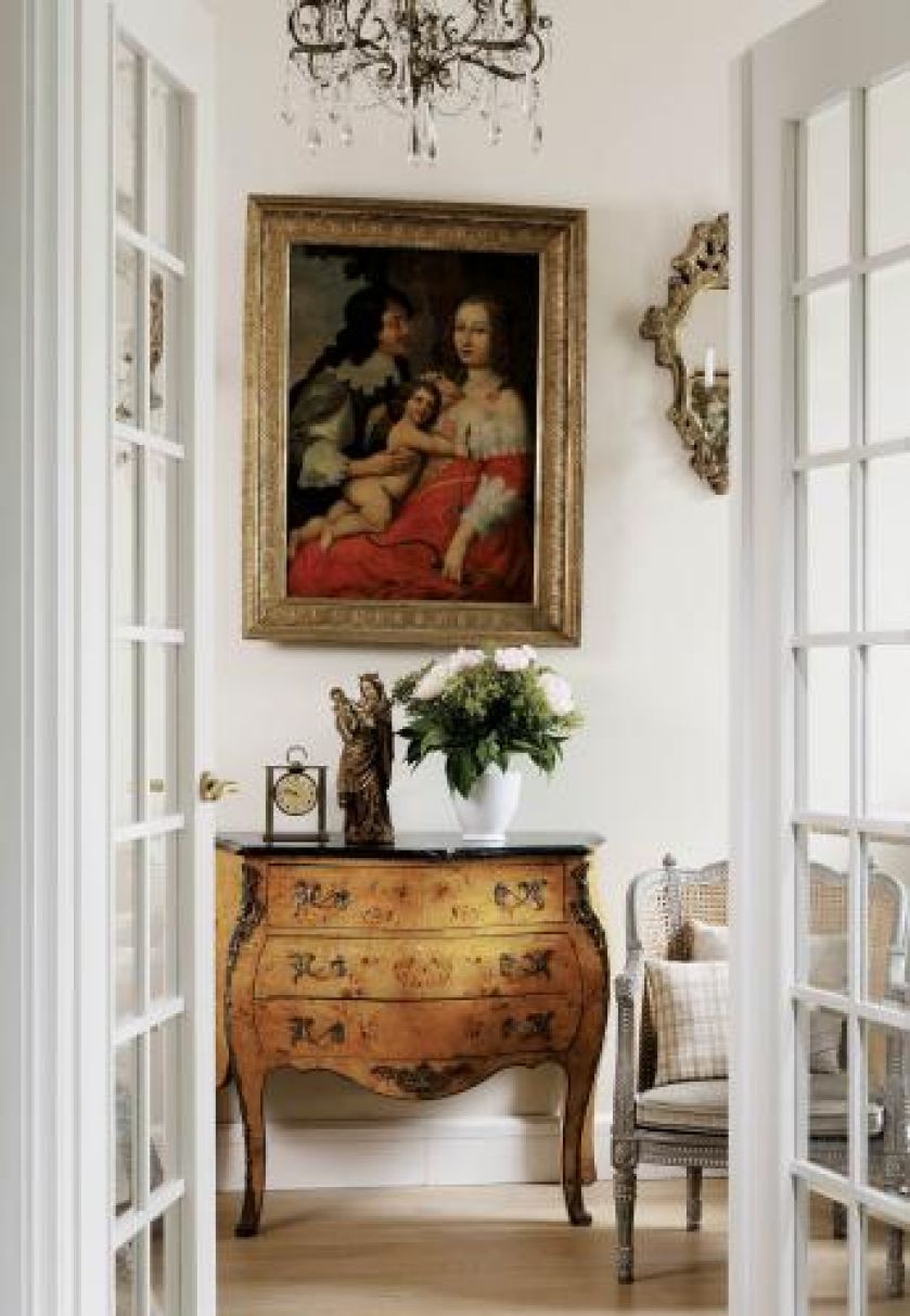 Nad komodą wisi obraz w zloconej ramie.