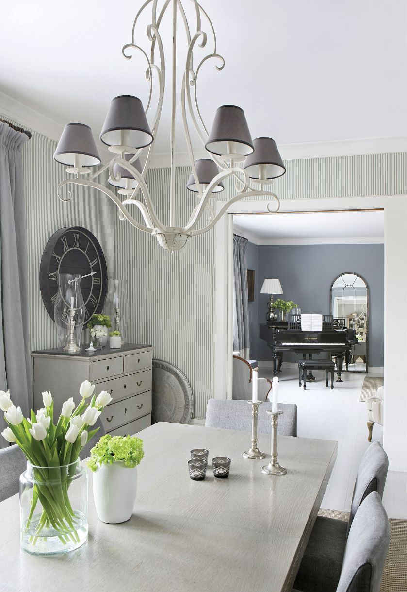 Tapeta w drobne paski, ozdobny żyrandol i świeczniki - dekoracje są dobrane idealnie.