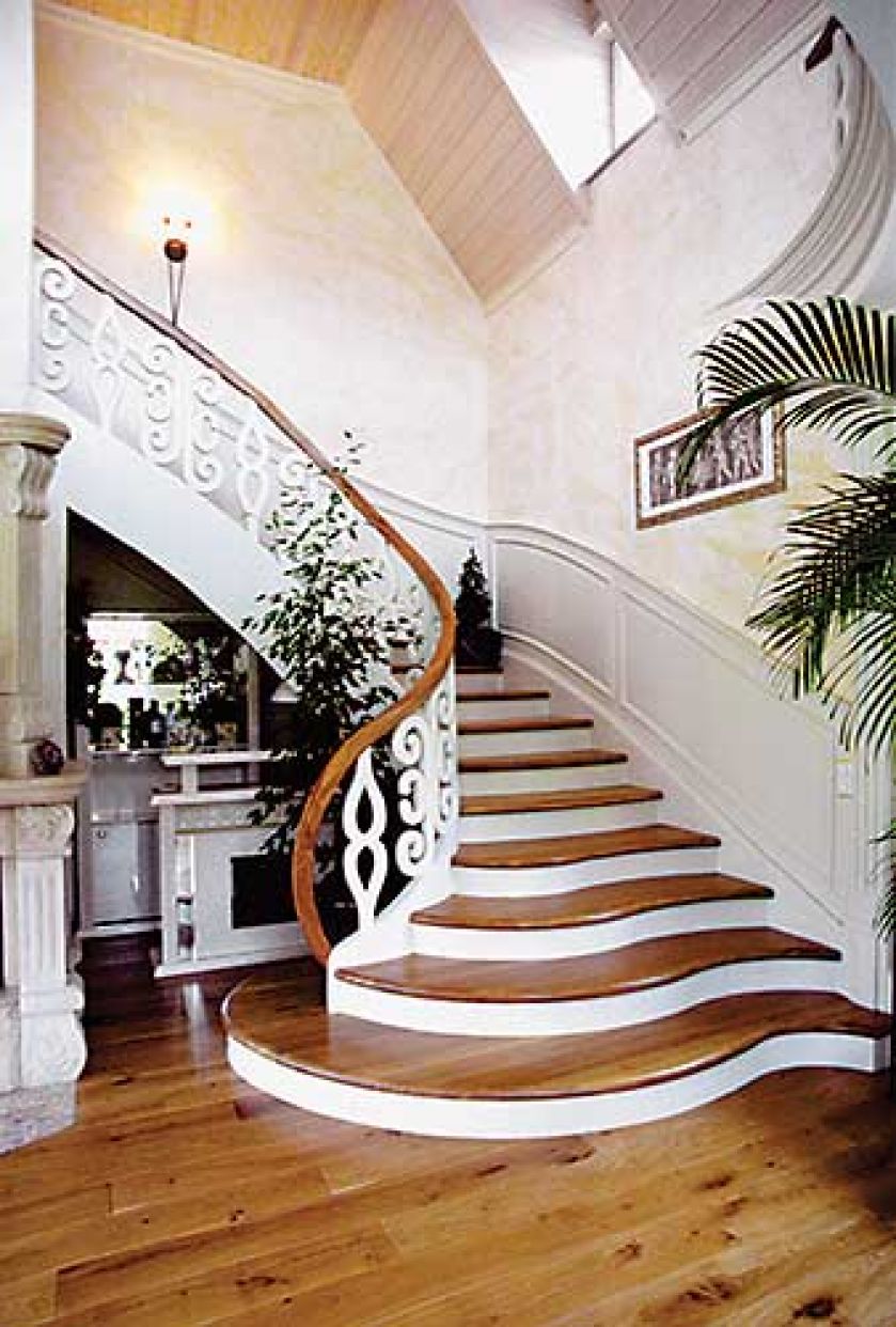 Schody z litego drewna wykończone półokrągłymi stopniami. Balustrada z kutego żelaza. PRACOWNIA SCHODÓW PAZURA