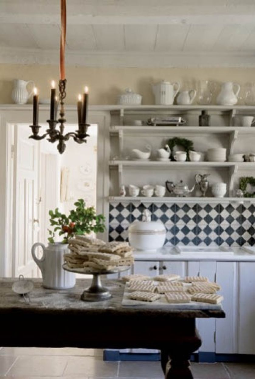 Kuchenne szafki i półki zrobiono na zamówienie ze starych drzwi do stodoły. Pomalowane na biało ładnie komponują się ze