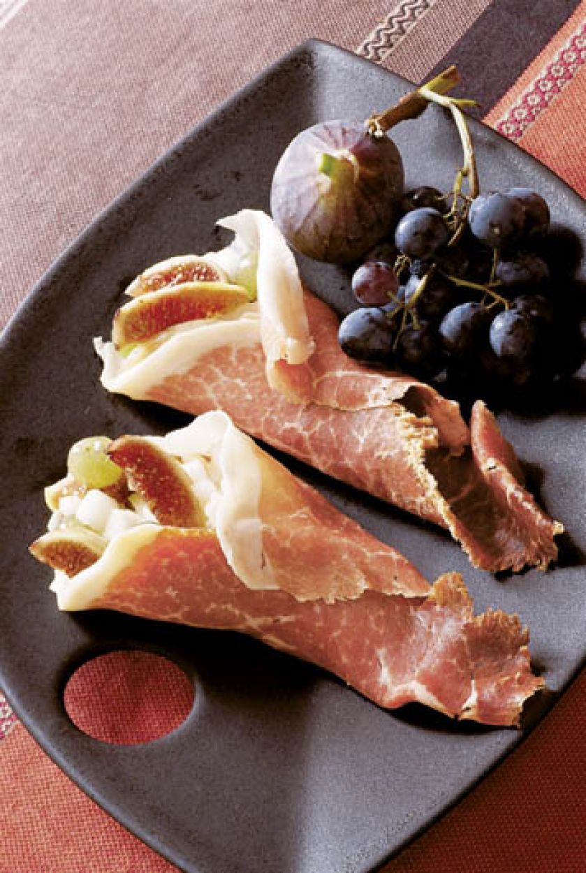 Jabłka, gruszki, winogrona i figi zawinięte w plastry szynki parmeńskiej.