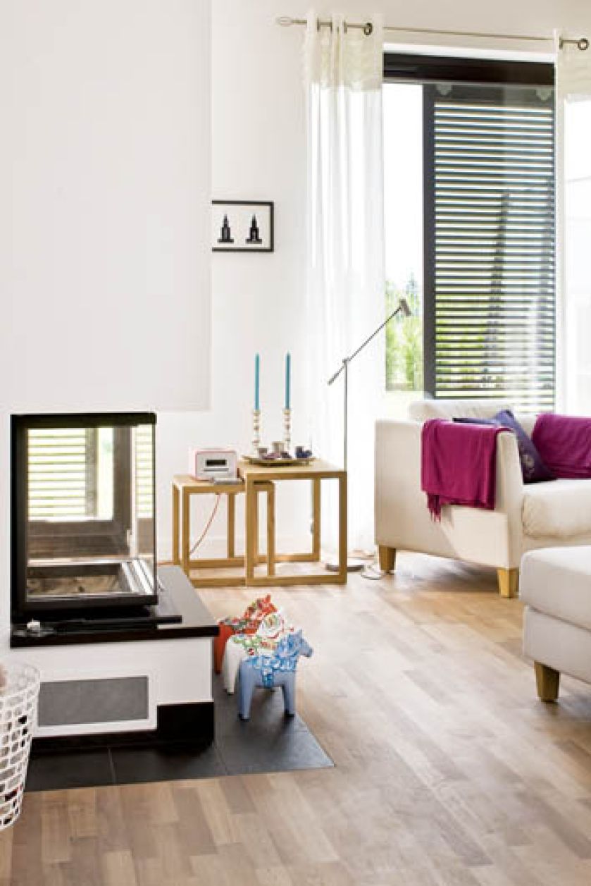 Białym ścianom towarzyszą kolorowe akcenty - zasłony, grafiki na ścianach i poduszki.