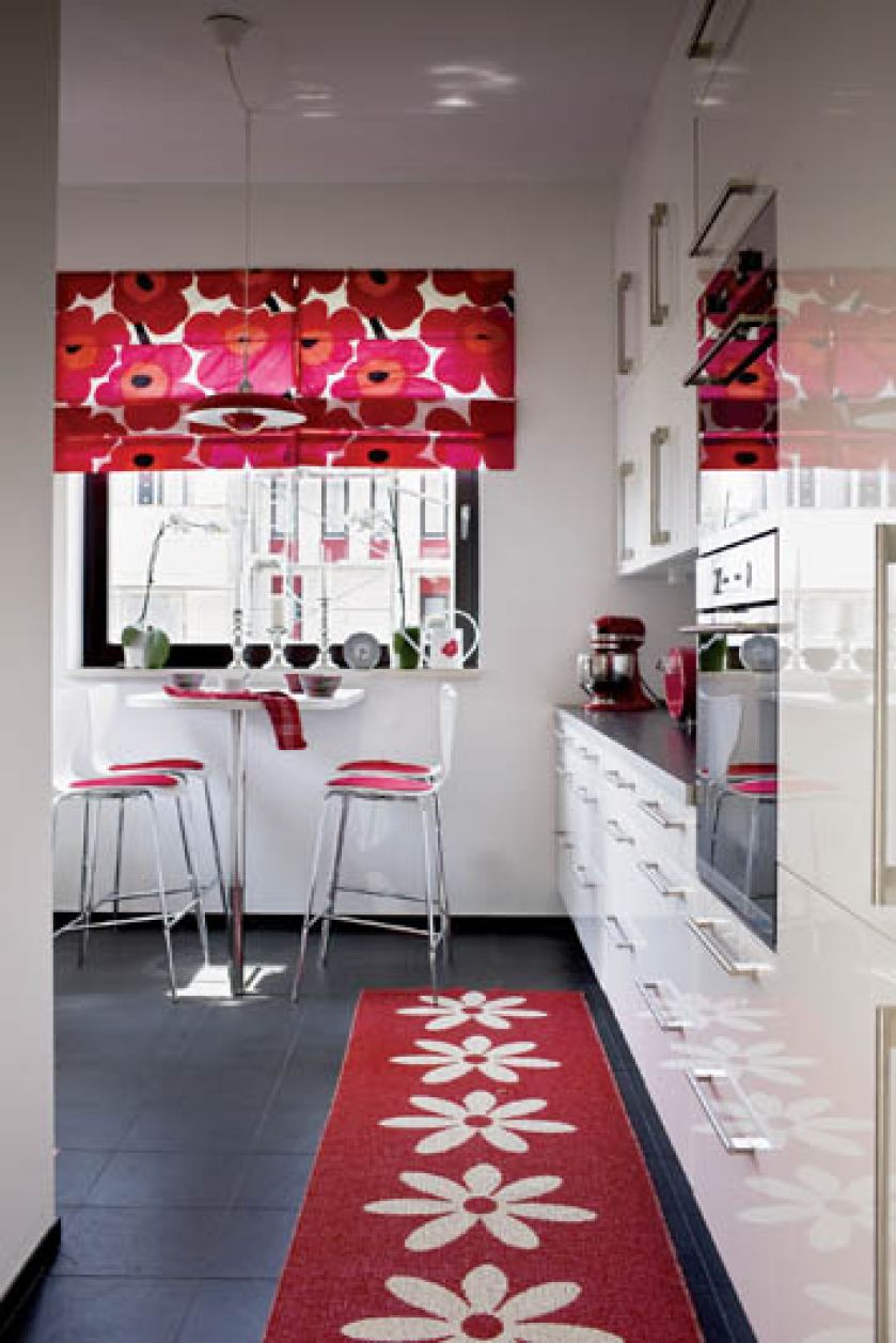 Chłodna biel szafek i płytki na podłodze łagodzą intensywną czerwień.