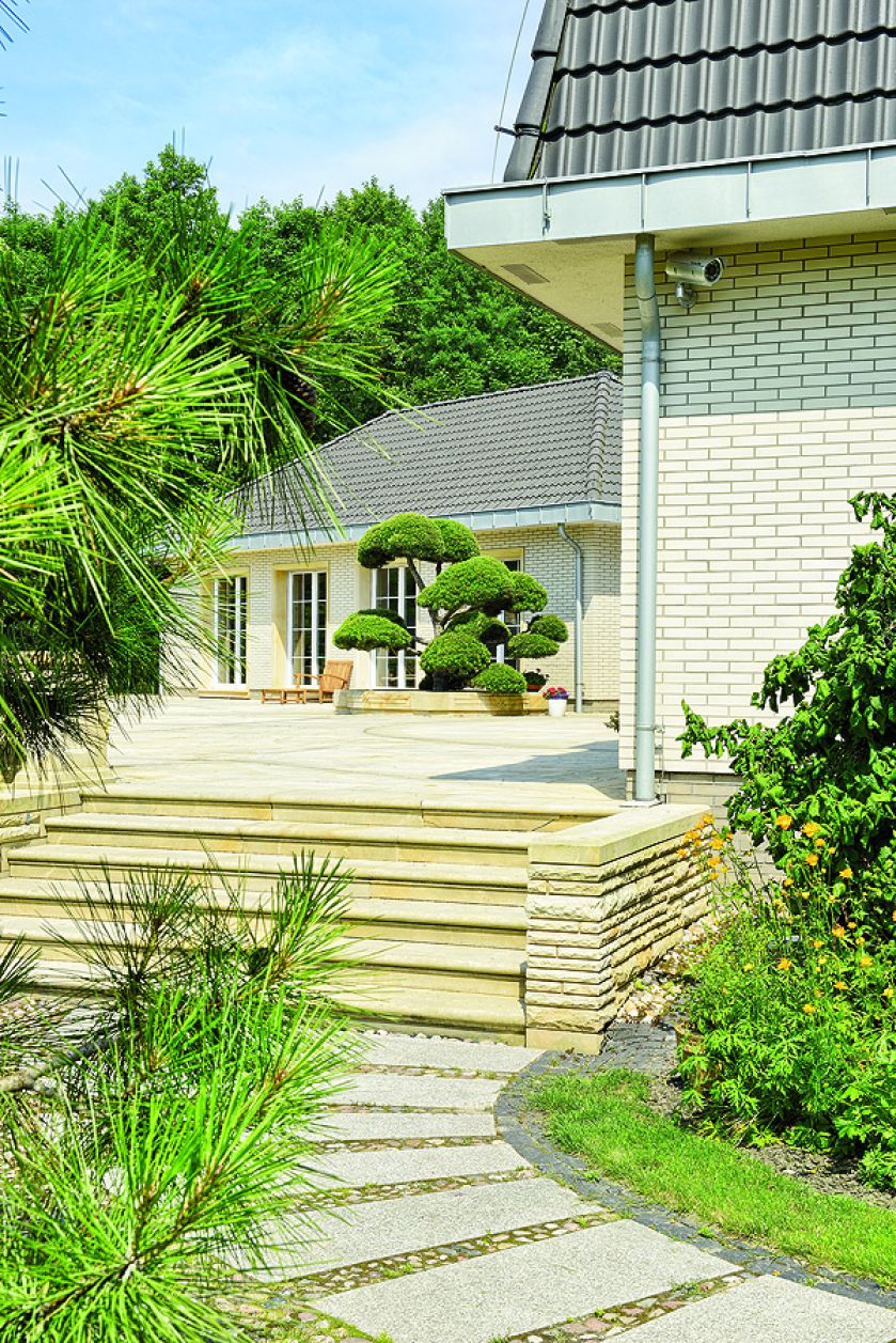 Duży dom w stylu amerykańskich rezydencji znika w bujnej zieleni.