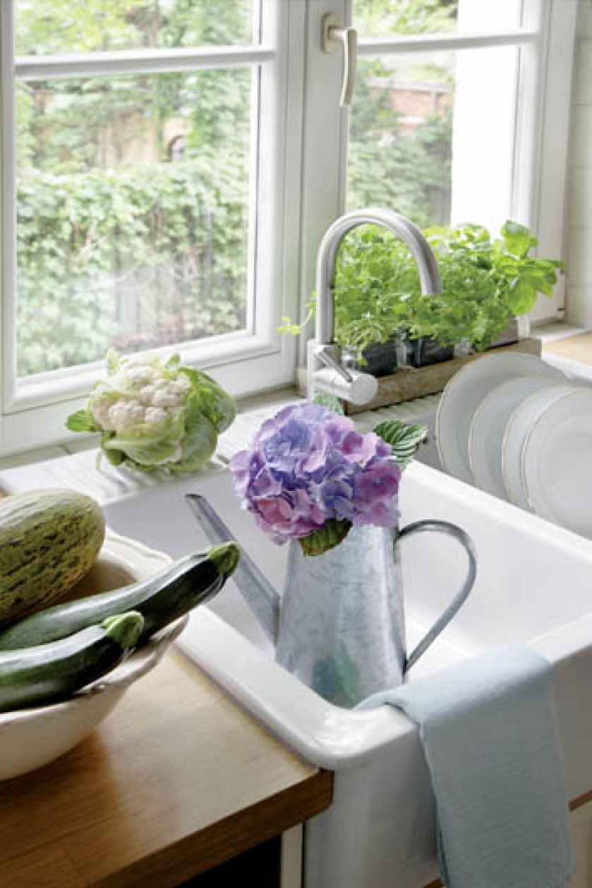 Świeże zioła w doniczkach na parapecie i warzywa i kwaty hortensji - ulubienicy pani domu.