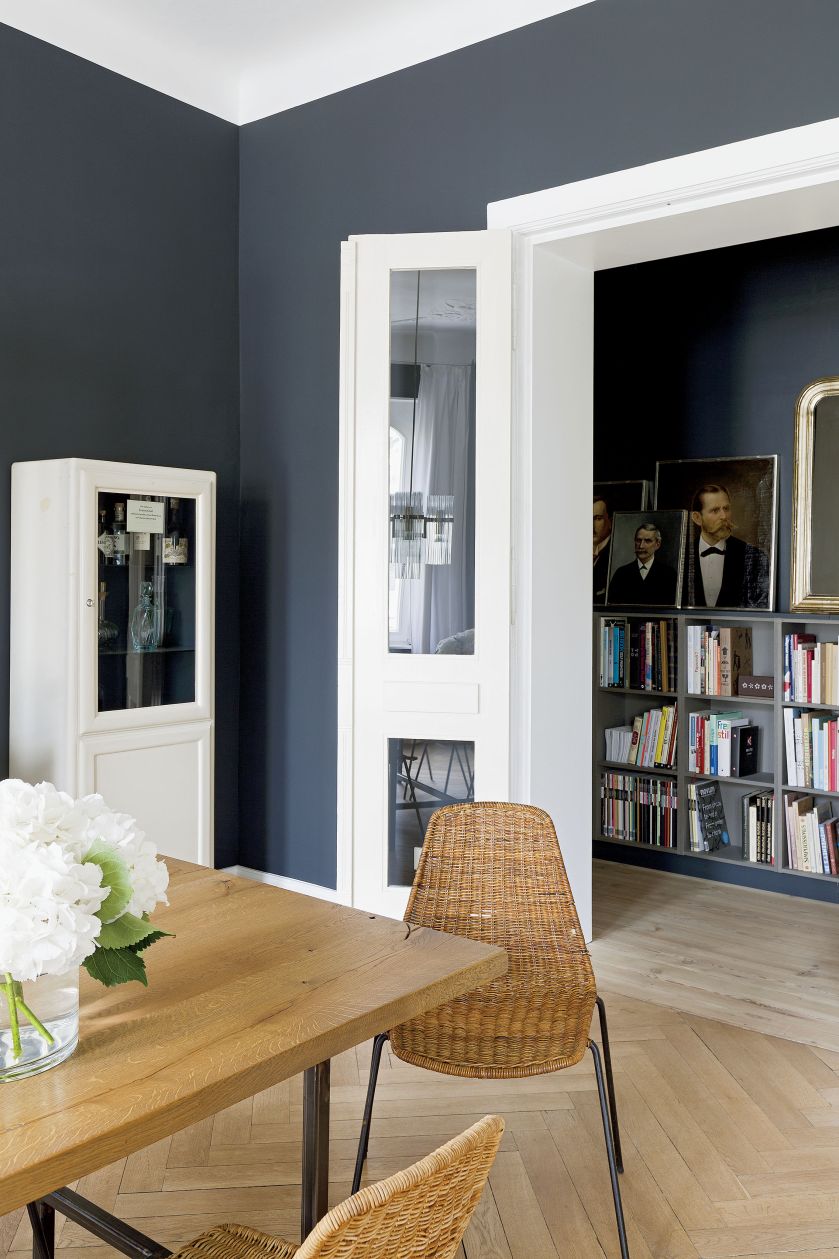 Wokół stołu stoi osiem wiklinowych krzeseł Basket Chair Giana Franca Leglera. Nad stołem żyrandol Gaetana