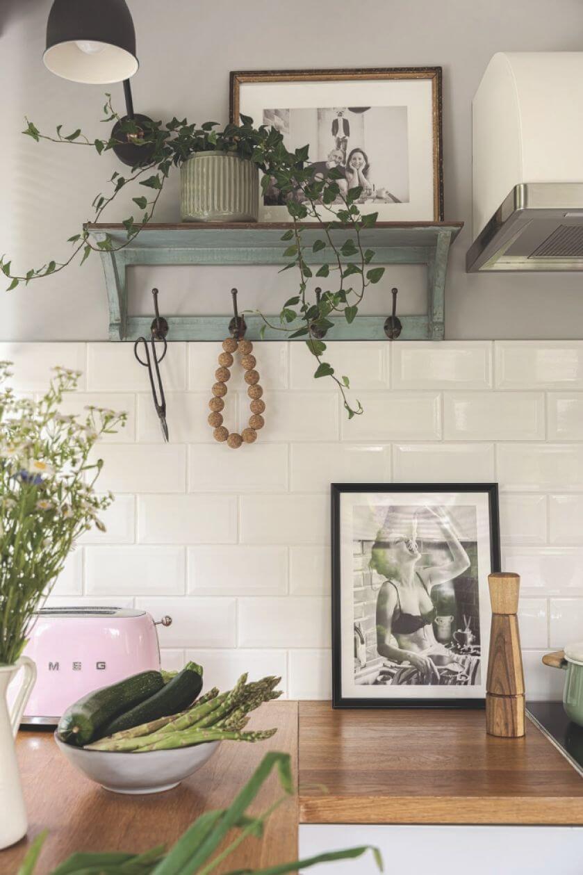 biała kuchnia z drewnianym blatem i zielonymi akcentami