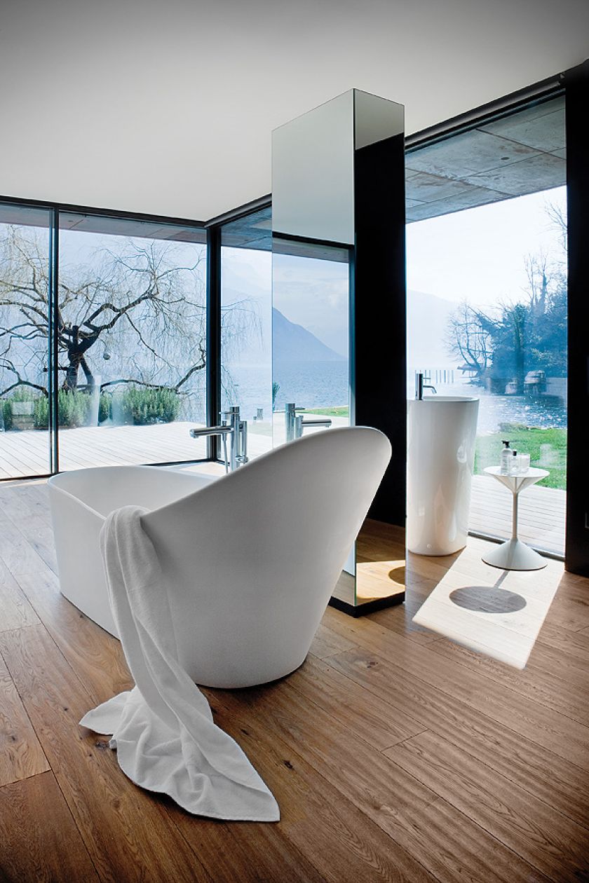 Drewniana podłoga, szklana ściana i drewniany taras. Łazienka zaprojektowana przez Ludovicę i Roberta Palombów. Umywalka