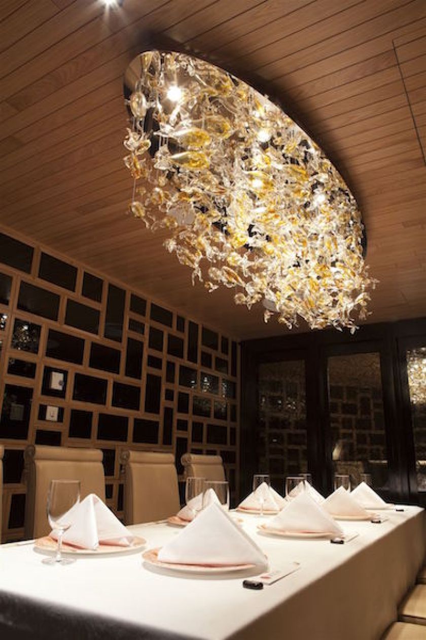 Kompozycja szklano-świetlna nad stołem w jadalni, wykonana z ręcznie formowanych, kolorowych elementów szklanych