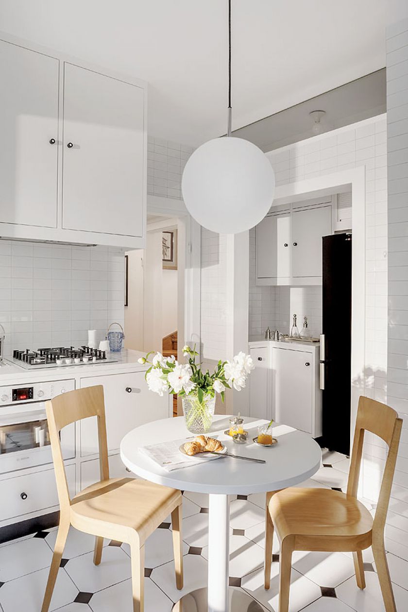 Kuchnia urządzona na biało - piękne kafle na ścianie i płytki na podłodze - w charakterystycznym dla międzywojnia kształcie i rozmiarze.