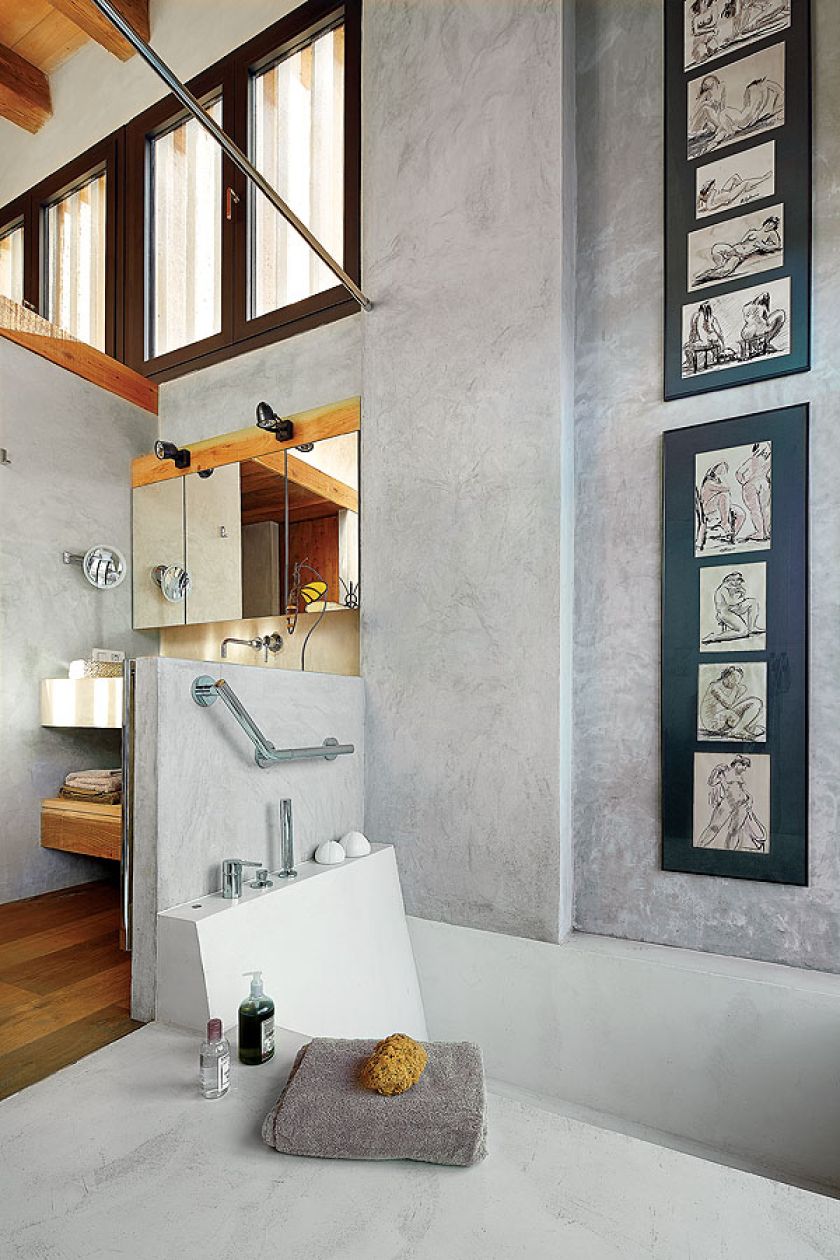 Nawet w łazience na ścianie wisi sztuka: do betonowych ścian pasują grafiki oprawione w antyramę.