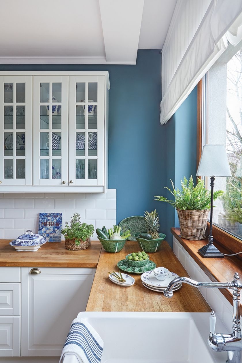 niebieska kuchnia z białymi szafkami i drewnianym blatem