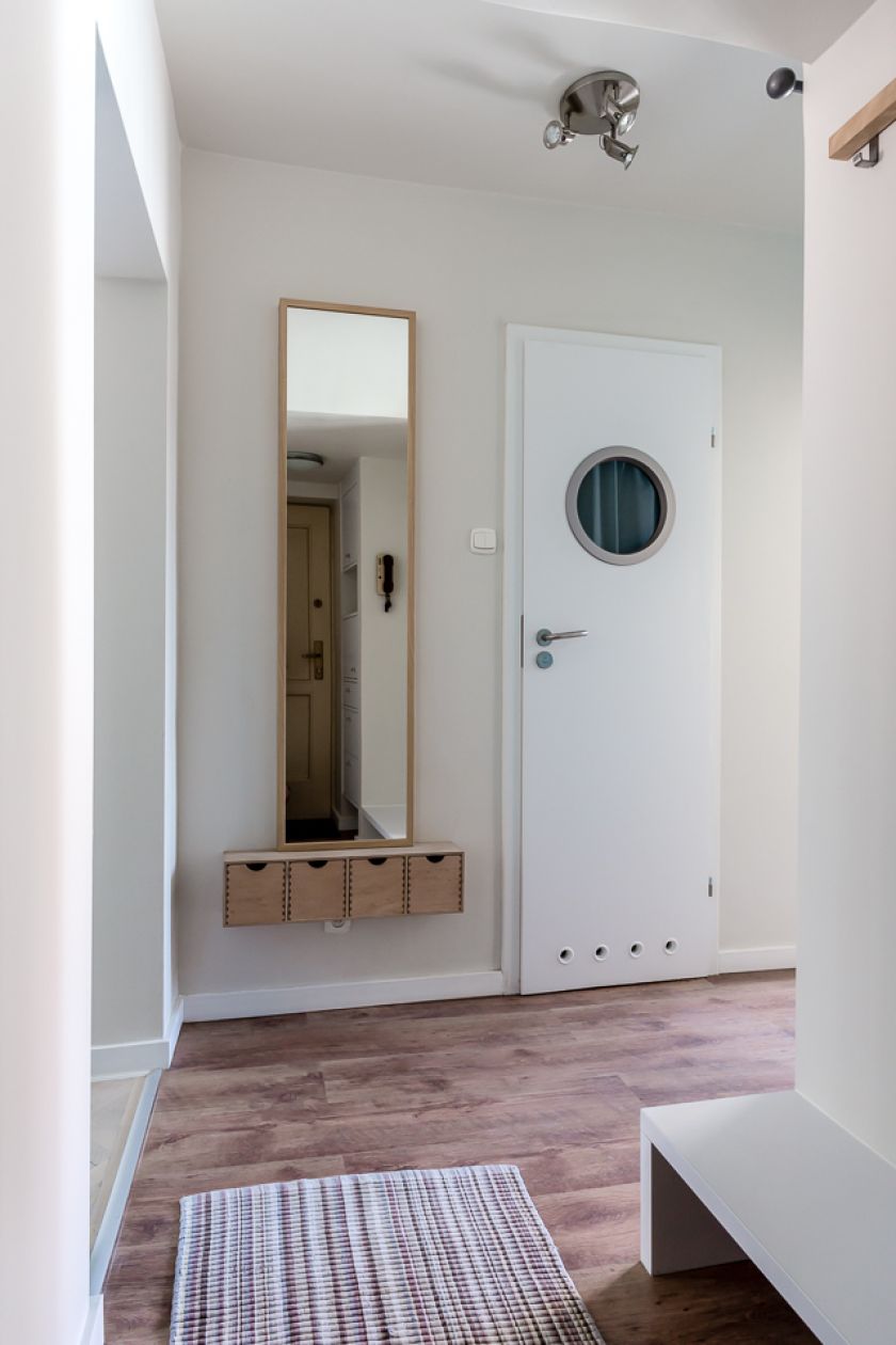 W małym przepokoju zastosowano minimalistyczą aranżację: lustro z zawieszoną pod nim półką z szufladami.