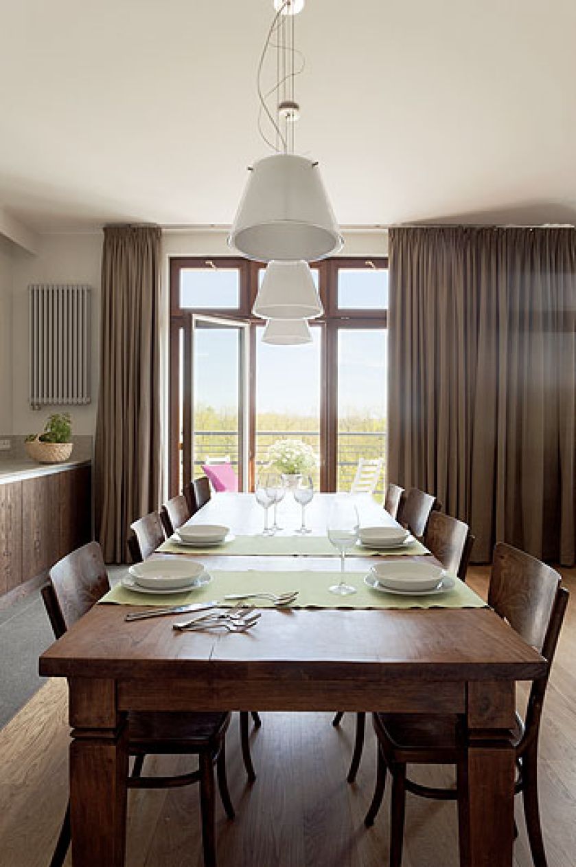 Duży rodzinny stół stoi między kuchnią a salonem.