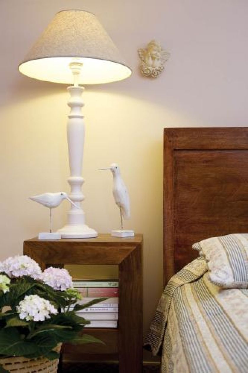 Na szafce obok lampy stoją figurki drewnianych ptaków.