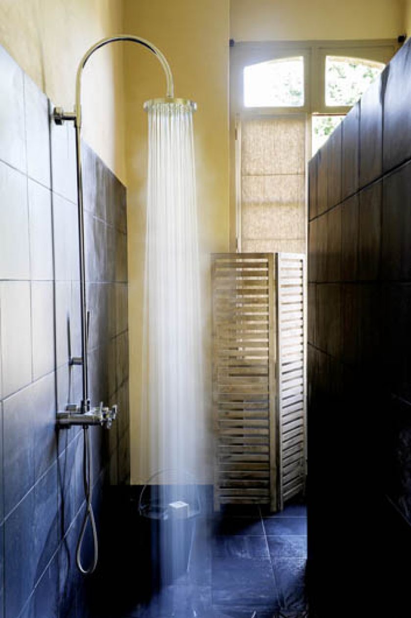 Plytki ze szlifowanego betonu i bateria w industrialnym kształcie kontrastują z cieplym kolorem ściany i naturalnym drewnem.