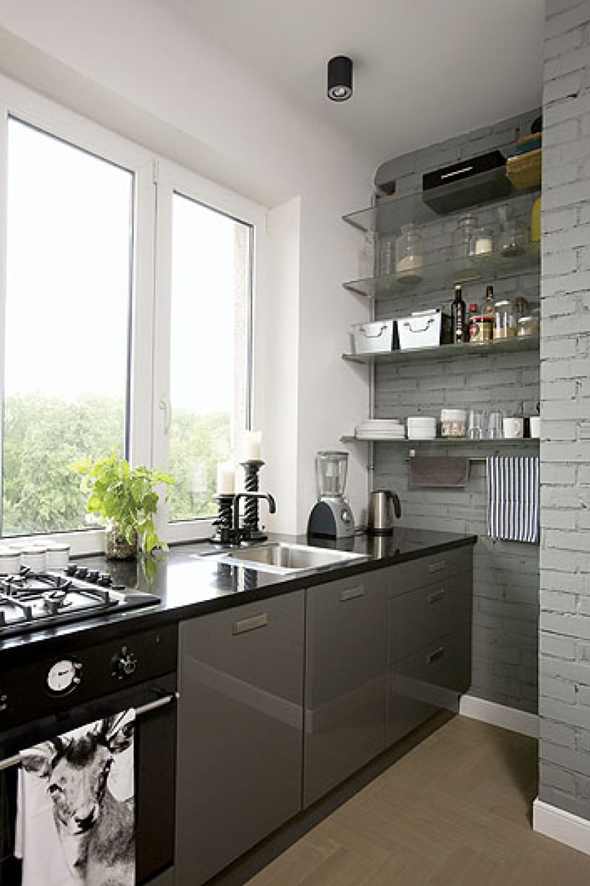 Proste, nowoczesne szafki wyglądają bardzo dobrze obok surowej ściany z cegieł.