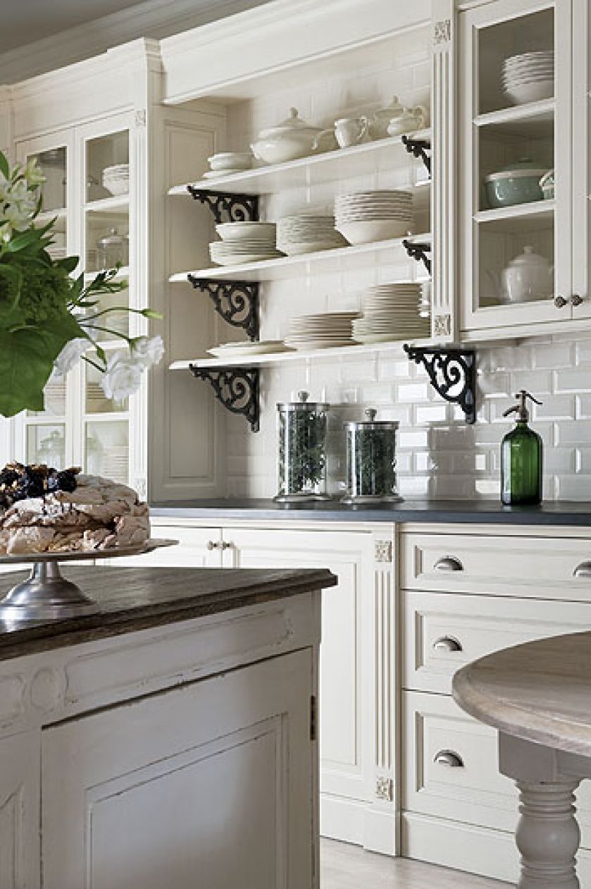 Stylizowana, biała kuchnia. Półki z dekoracyjnymi, żeliwnymi wspornikami. FABRYKA WNĘTRZ