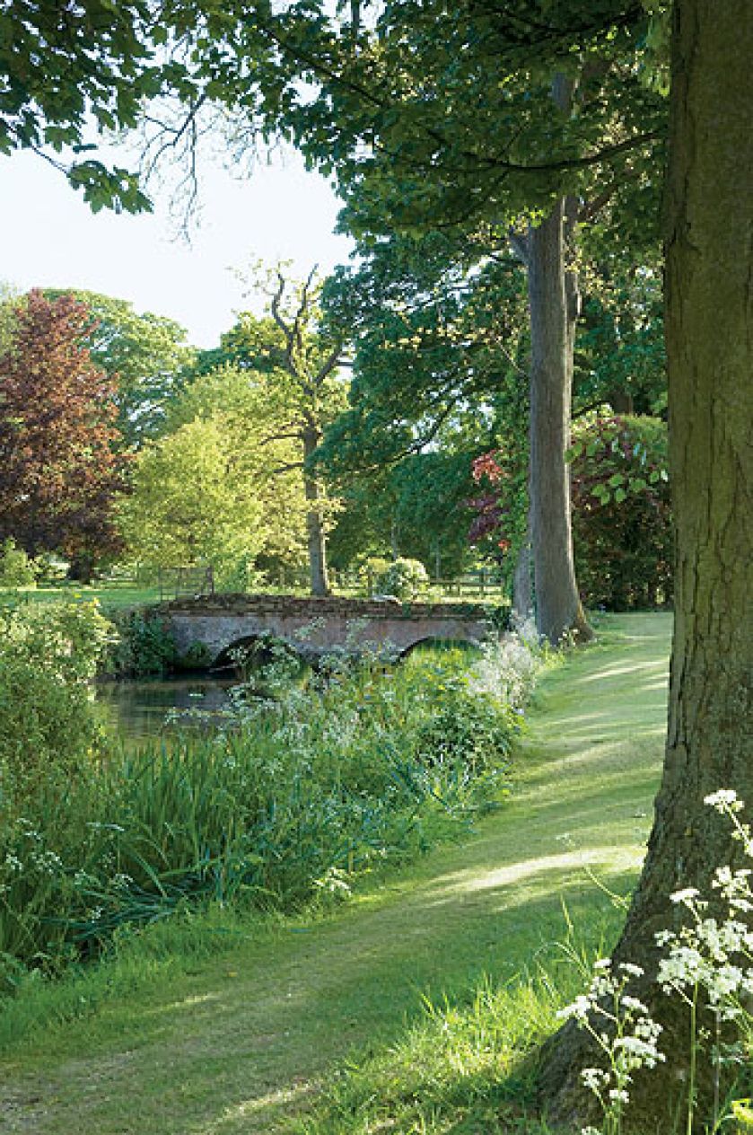 Dwa hektary otoczone wodą, z resztkami starych ceglanych murów, różanymi pergolami, równiutkimi żywopłotami. Im dalej