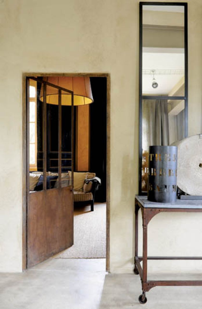 Surowe blaszane sprzęty, a w głębi za drzwiami - stylowa kanapa.