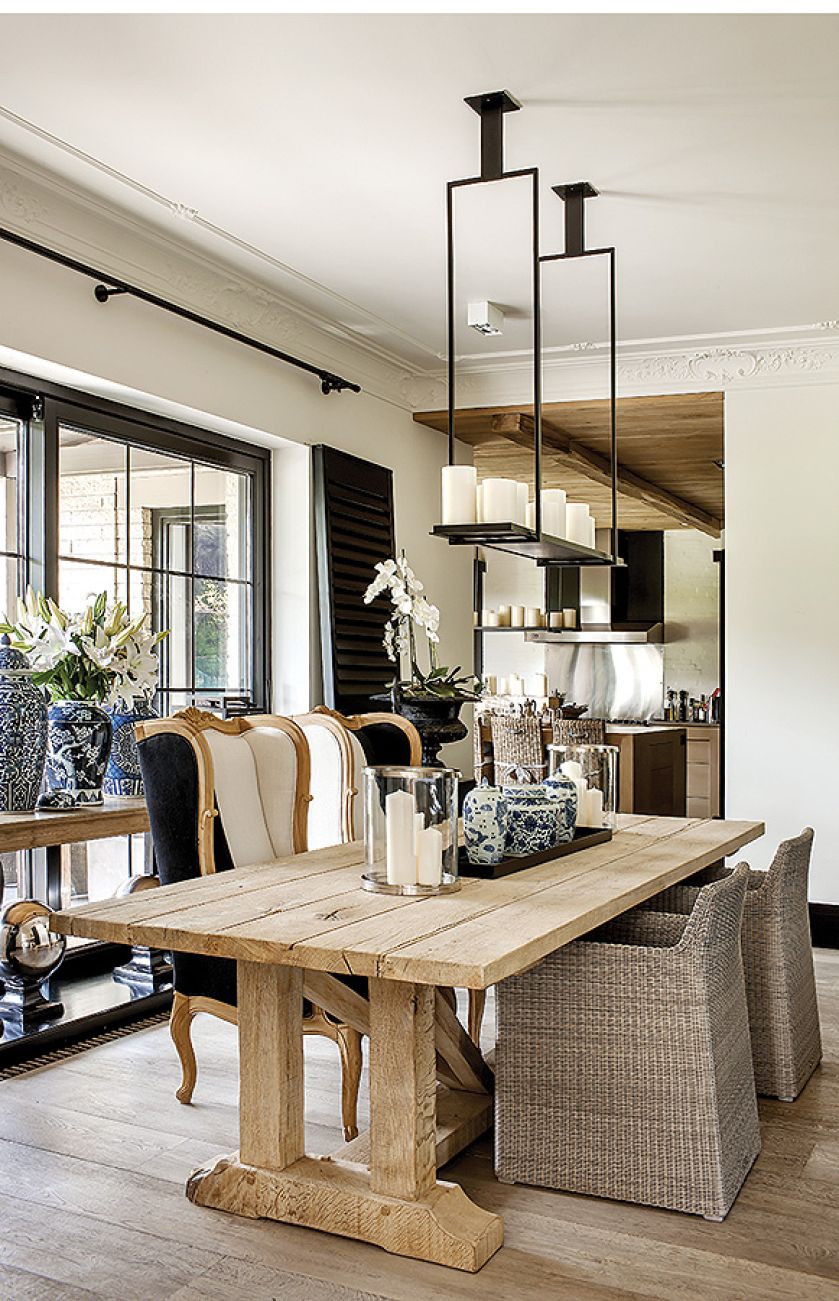 W jadalni rustykalny stół na tle ogromnego okna, a po prawej i lewej czarne kolumny ze stylowymi wazami