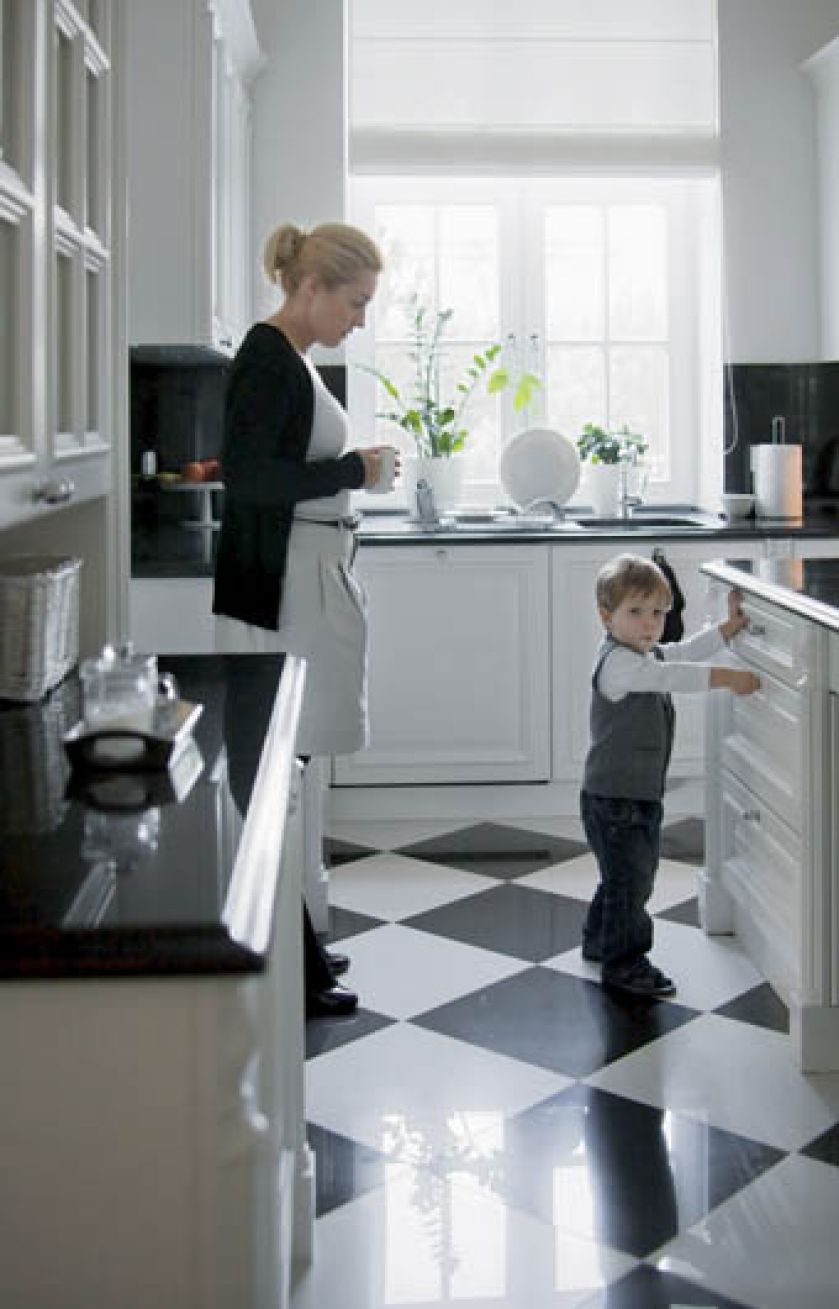 Szachownica na podłodze w kuchni i blaty z czarnego kamienia harmonozują z całością wystroju.