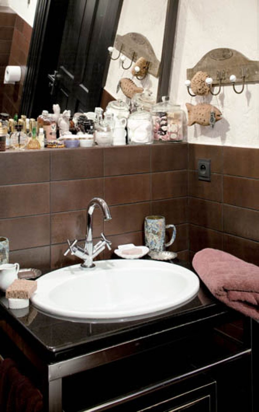 W łazience świetnie sprawdza się połączenie piaskowej ściany z brązowymi płytkami.