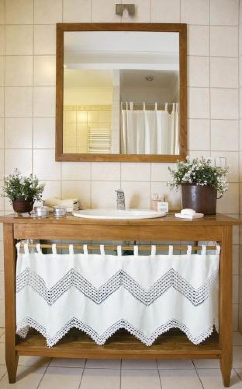 W łazience jasne płytki i drewniane meble.