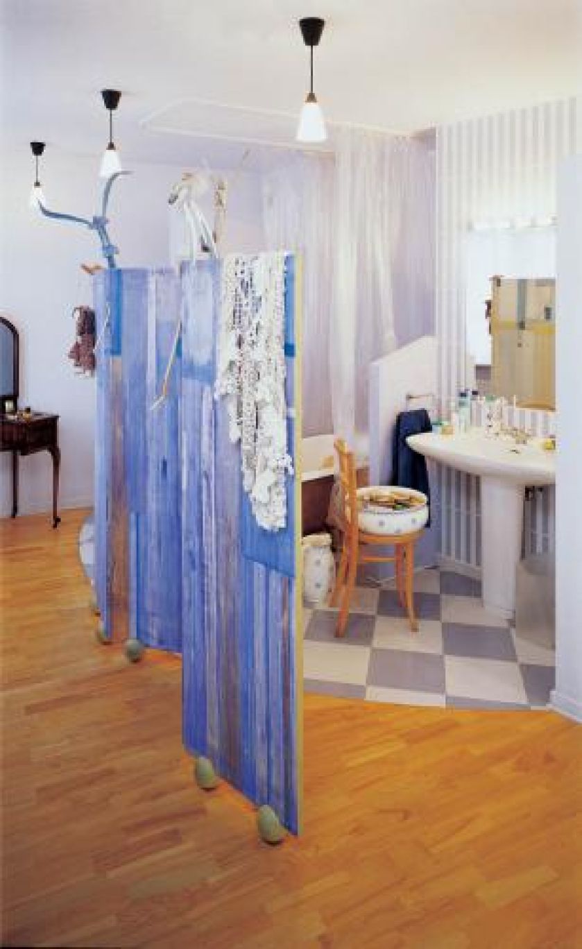 Część sypialną od kąpielowej dzieli tylko parawan pokryty błękitną tkaniną.