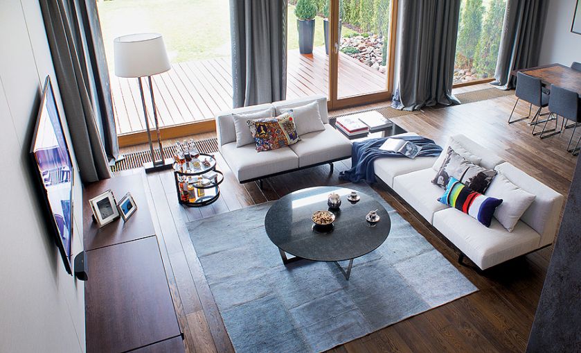 Podłoga z barwionego dębu to dzieło firmy Nelo-One. Kanapy na zamówienie - Zwara. Poduszki i dywan - Decodore Basic.