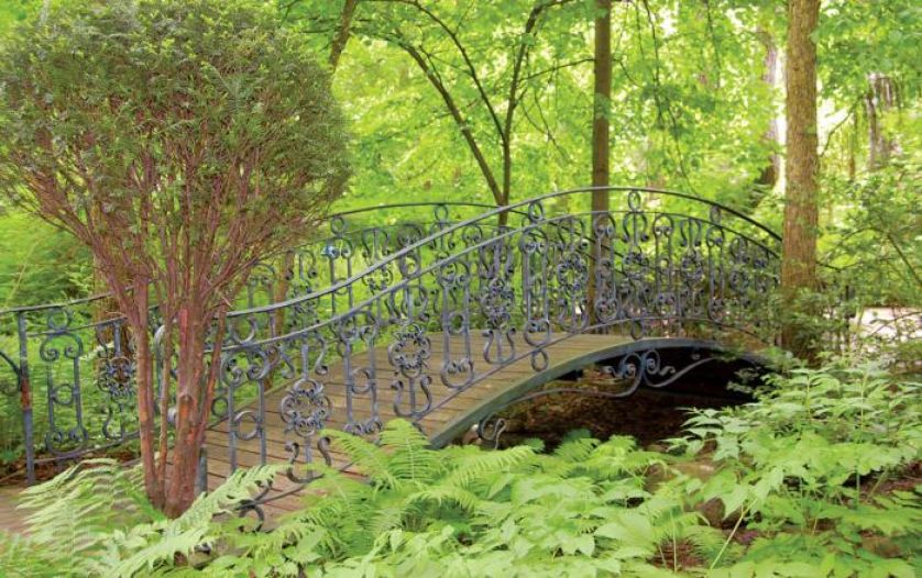 W ogrodzie mostek ze zdobioną balustradą.