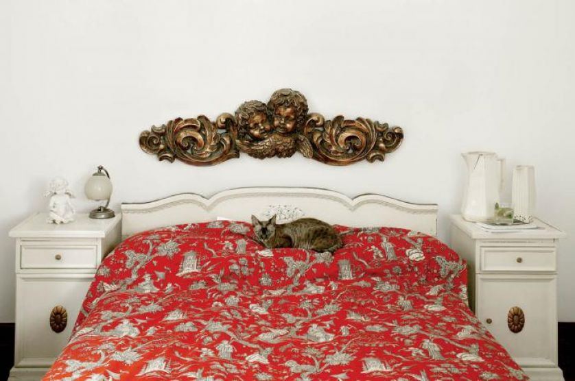 Nad łóżkiem wisi płaskorzeźba przedstawiająca puttę.