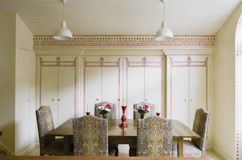 W kuchni stół i krzesła obszyte wzorzystymi tkaninami.