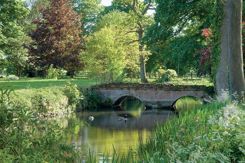 Dwa hektary otoczone wodą, z resztkami starych ceglanych murów, różanymi pergolami, równiutkimi żywopłotami. Im dalej