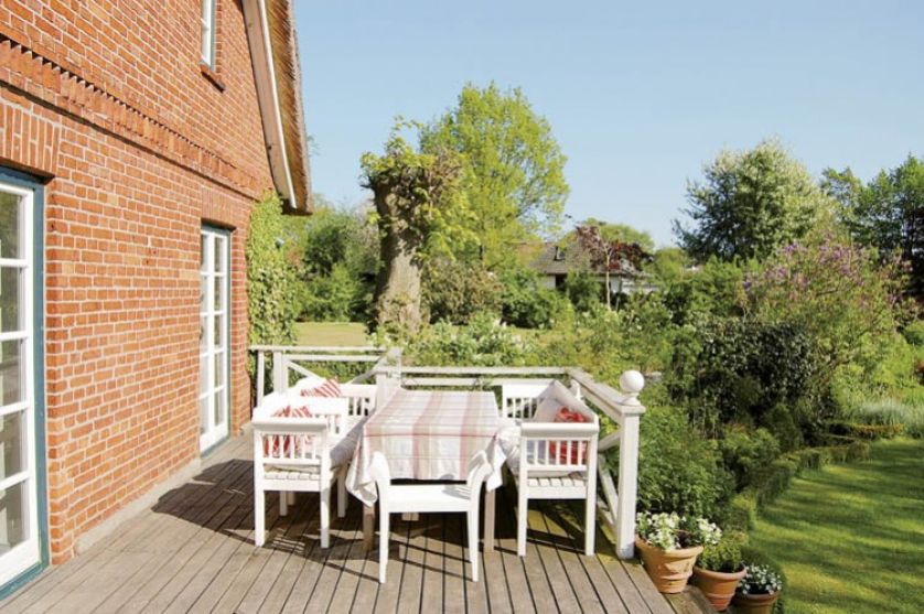 Z drewnianego tarasu schodzi się wprost do ogrodu - dumy właścicieli.