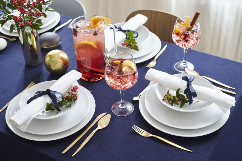 Mocne zestawienie kolorów: granatowy obrus, złote, złote sztućce i czerwień świątecznych napojów.