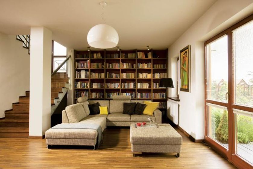 Biblioteka marzeń właścicieli - z przepastnym regałem fornirowanym ciepłym drewnem orzechowym i wygodną kanapą w