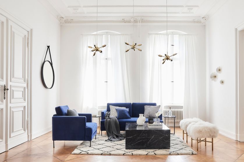 granatowa sofa i marmurowy stolik kawowy w salonie