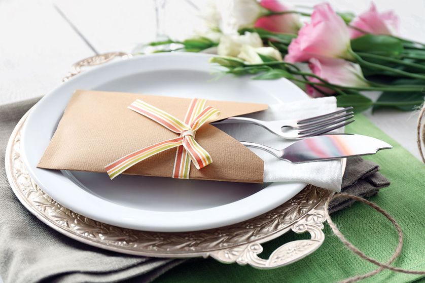 Sztućce i serweta wetknięte w papierową kopertę z kokardą - oryginalnie