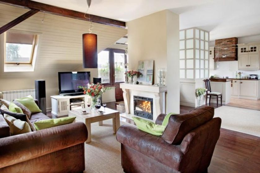 Zielone poduszki kontrastują z brązową kanapą i fotelem.