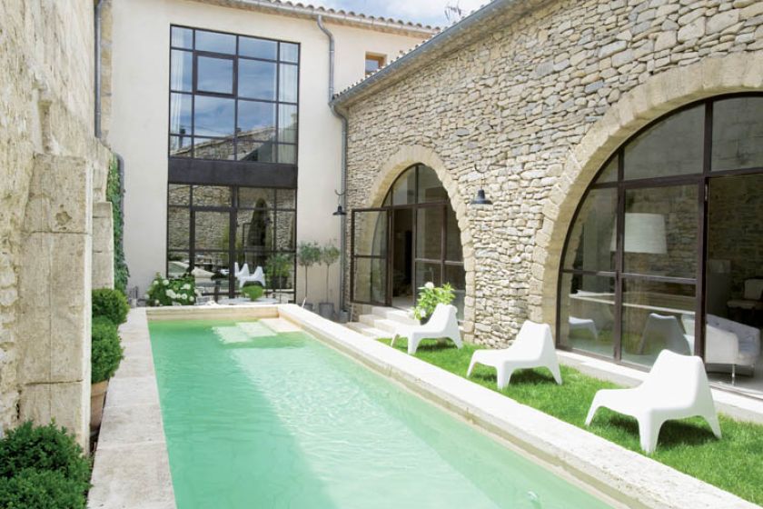 Basen ma 9 metrów, pas trawy, dookoła stoją terakotowe donice z hortensjami i bukszpanem.