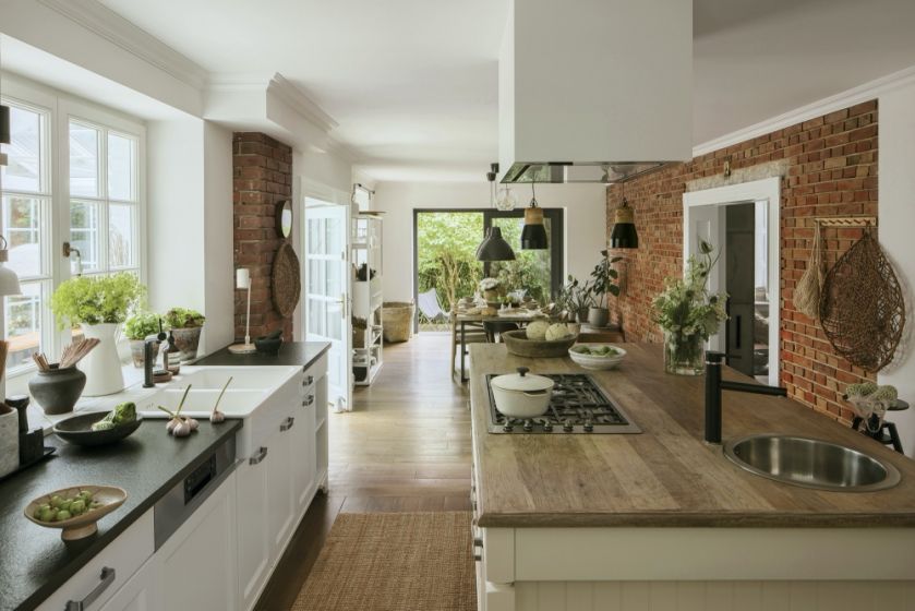 biała kuchnia z drewnem i czerwoną cegłą