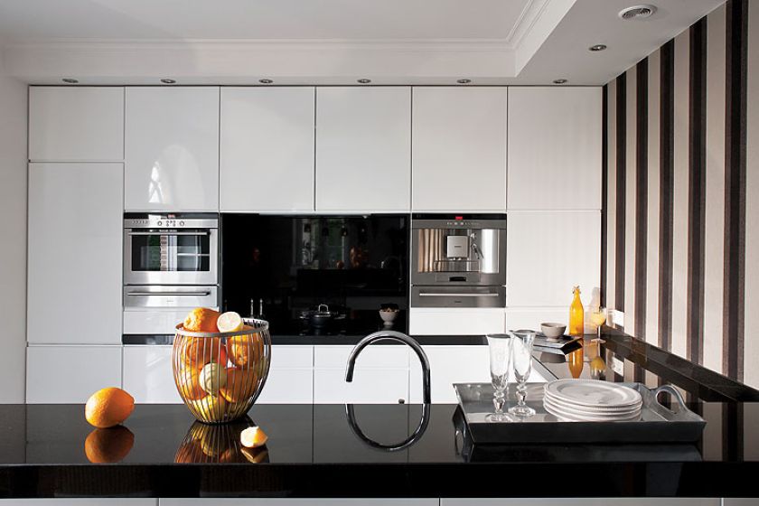 Biało-czarna nowoczesna kuchnia wycisza rozmach reszty domu. Nie brak w niej ciepłuch akcentów: pasiastej tapety