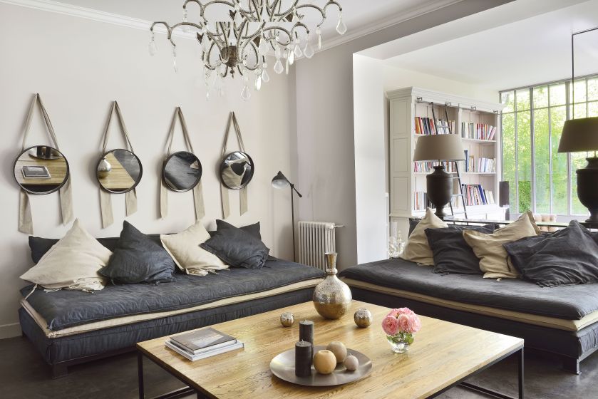 Wokół dużego stołu kawowego dwie sofy marki Zina, inspirowane marokańskimi leżankami. Na ścianach lustra zawieszone