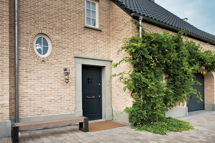 Ceglana elewacja, czarny spadzisty dach i minimalistyczny ogród.